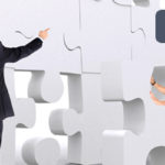 Business employees pushing large giant puzzle pieces into a wall made of giant puzzle pieces. A heading at the top of the images reads, "Solutions That Fit."
