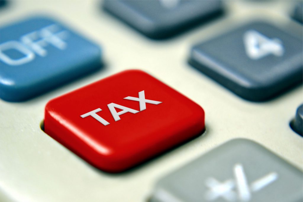 Close-up photo of a red button on a calculator that reads, "TAX."